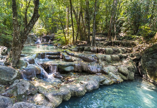 Tourists bathing in a waterfall in the Erawan National Park