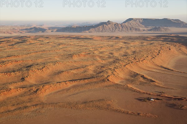 Farmhouse at the foot of a large grass-grown dune at the edge of the Namib Desert