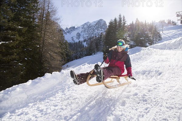 Young woman riding on a sledge