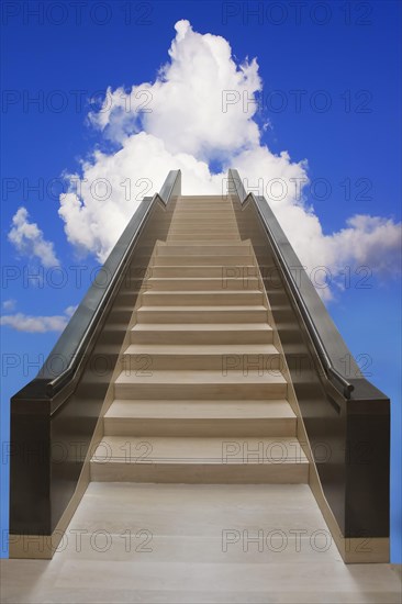 Long staircase leading up into the blue sky with white clouds