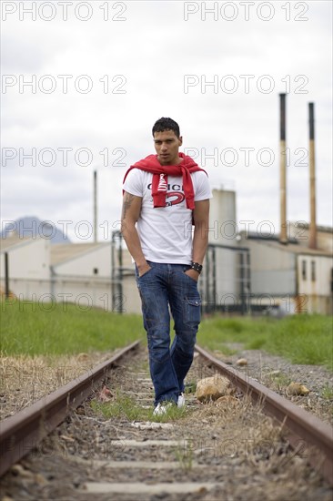 Young man walking on deserted railway