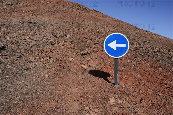 Blue sign with a white arrow pointing left