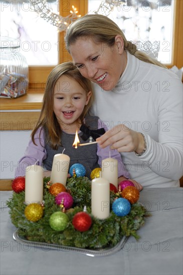 Mother and daughter lighting the first candle on the Advent wreath