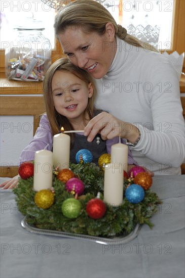 Mother and daughter lighting the first candle on the Advent wreath