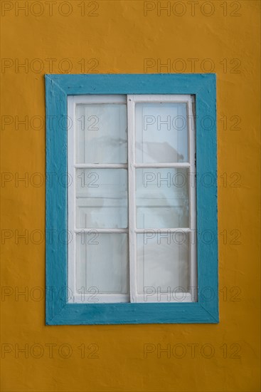 Turquoise coloured window with a yellow facade