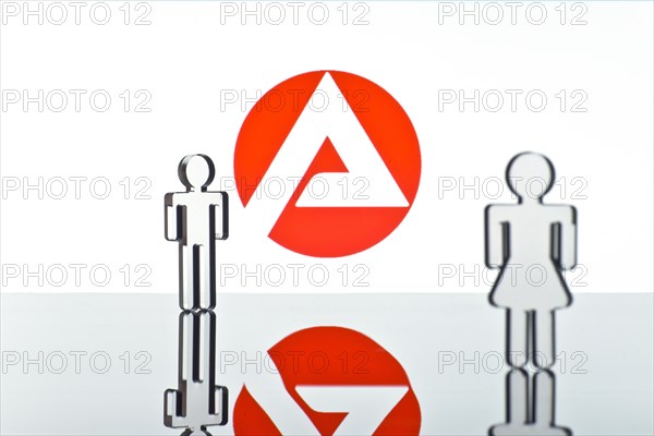 Two figures standing in front of the logo of the German employment agency