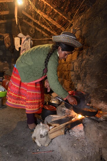 Young woman cooking on an open fire in her traditional kitchen