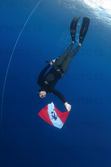 Freediver holds a diver down flag
