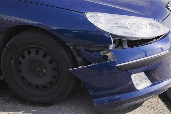 Blue compact car with an accident-damaged front bumper