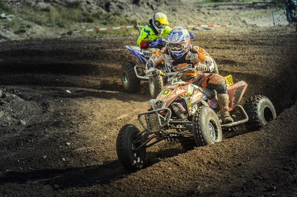 Two quad bikes speeding through a curve on a motocross track