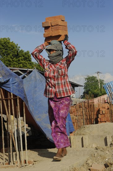 Female construction worker carry bricks on their heads