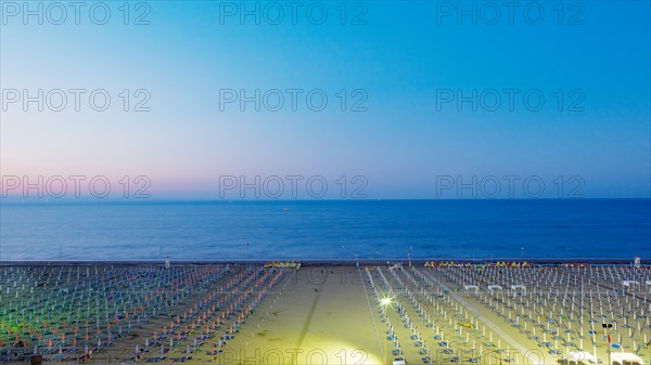 View of a beach with sunshades and sun beds at twilight