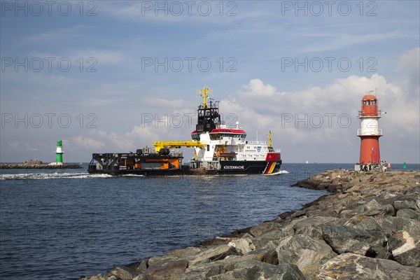 Coast Guard vessel passing two lighthouses at the harbor entrance