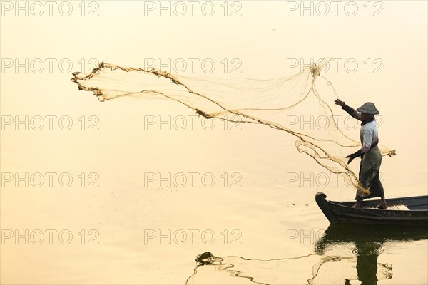 Fisherman in a boat tossing out a net