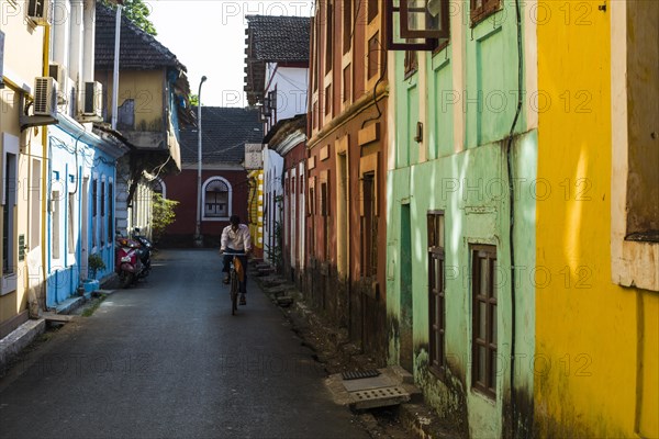 A small lane with colourful houses and a cyclist