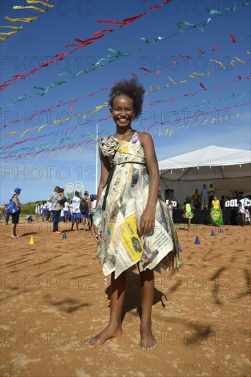 Girl presenting a dress made of recycled newspapers at a fashion show of a social project