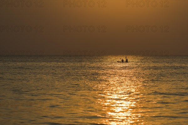 Two kayakers in the open sea at sunset