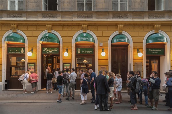 Tourists wait in long queues in front of the famous Schnitzel restaurant Figlmuller