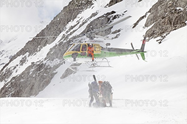 A helicopter is landing on the glacier at Cavardiras to transport people into the valley