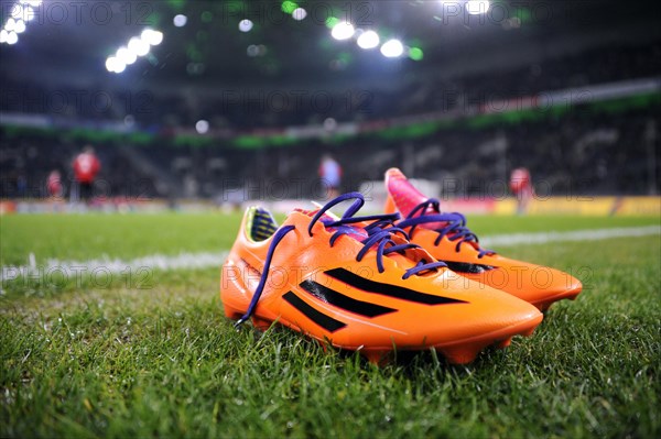Orange-coloured Adidas football boots on the edge of the pitch