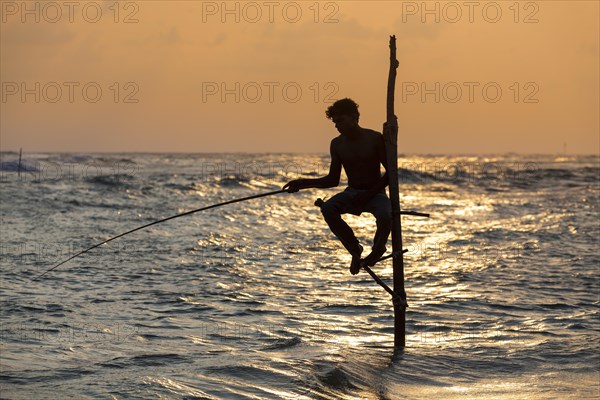 Stilt fisherman fishing in shallow water