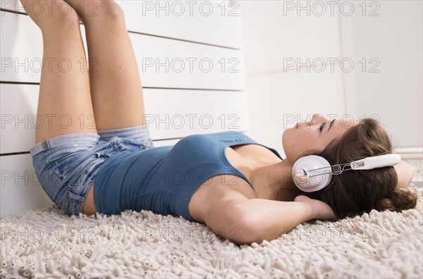 Woman wearing headphones lying relaxed on the floor