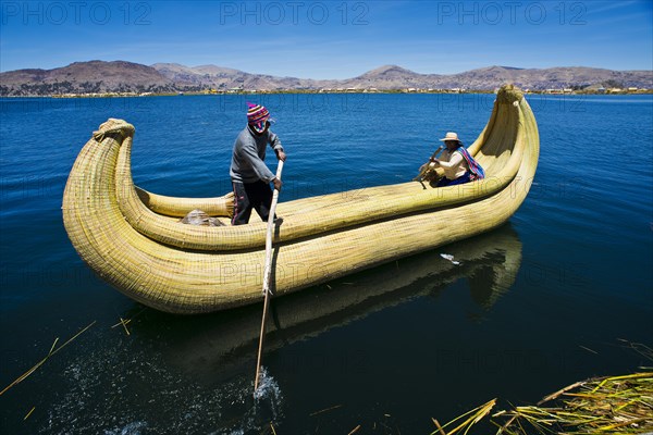 Two local people rowing a traditional boat made of totora reeds on Lake Titicaca