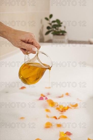 Woman pouring bath oil in a bathtub