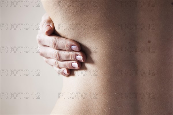 Bare back of a young woman with back pain