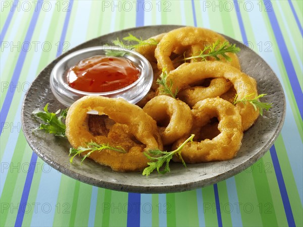 Deep fried breaded onion rings with chili sauce and salad