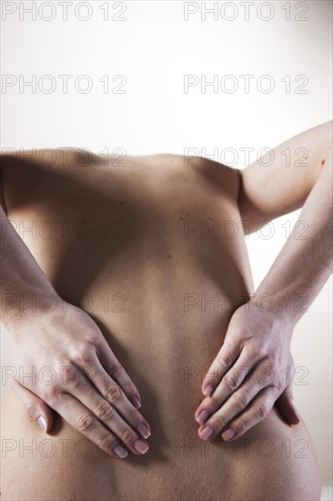 Bare back of a young woman with back pain