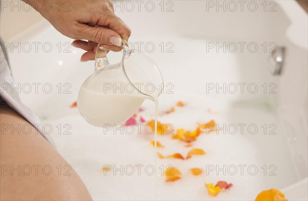 Woman pouring milk into a bath