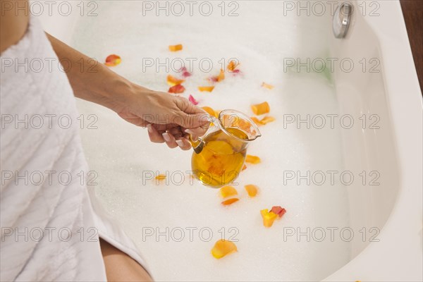 Woman pouring bath oil in a bathtub