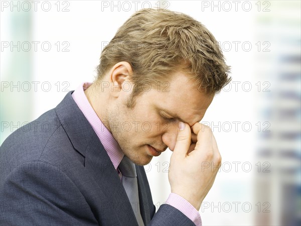 Stressed businessman holding a hand to the bridge of his nose