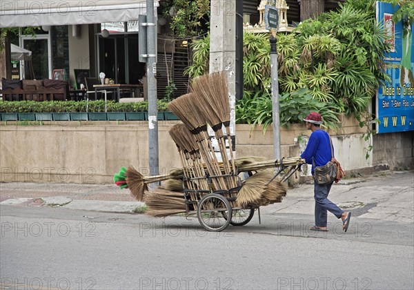 Broom merchant pushing his wares through the streets