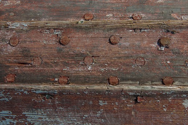 Weathered planks of a boat with residues of red paint
