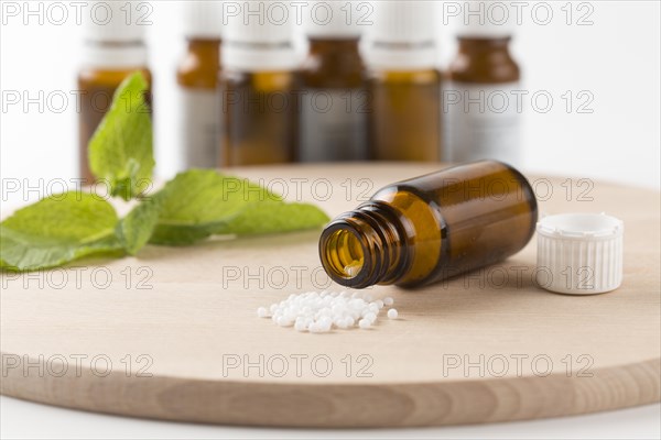 Open bottle with globules on a wooden board