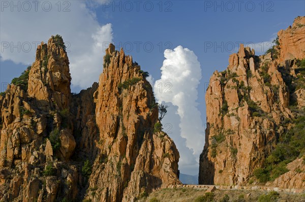 The typical bizarre red rocks of the Calanche of Piana below a blue sky and some clouds. The Calanche of Piana is in the western part of the island Corsica