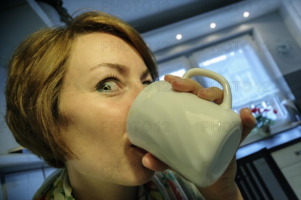 Young woman drinking coffee enthusiastically