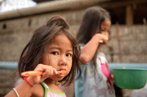 Two girls brushing their teeth outside a house
