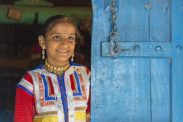 Young girl in traditional colorful clothes standing in a door