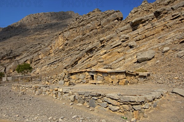 Bedouin stone house matching in colour and texture to the foot of a cliff in the mountains of Musandam