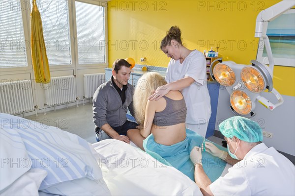 Pregnant women during delivery in the delivery room with an anesthesiologist applying a PDA or epidural