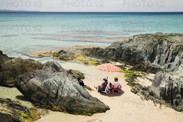 Couple sitting on the beach of Masua