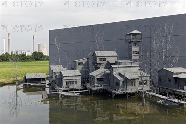 Village on stilts in front of an industrial scene