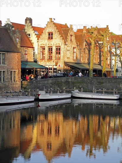Guild houses with stepped gables being reflected in a canal with boats