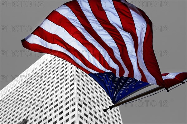 U.S.-American flag flying in front of a skyscraper