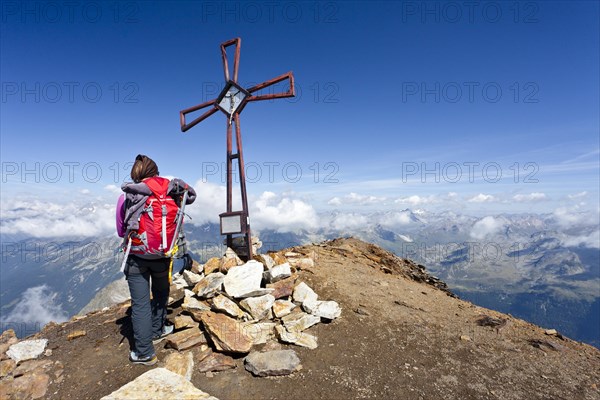 Mountain climber at the summit cross on Schneebiger Nock Mountain in the Rieserferner Group
