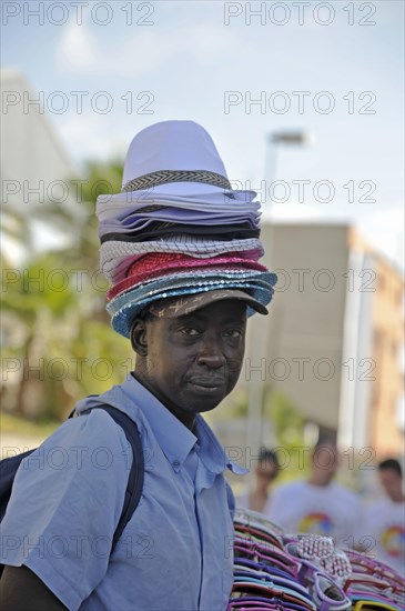 Hat seller with a stack of hats on his head