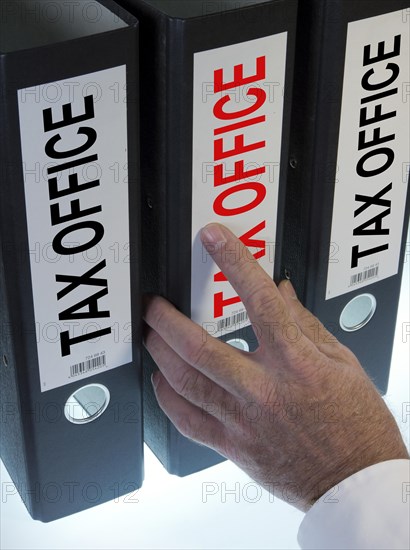 Hand reaching for file folders labeled 'tax office'